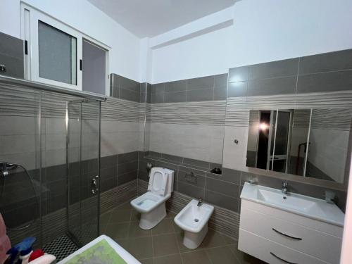 bagno con lavandino, servizi igienici e specchio di Ani Apartament a Durrës