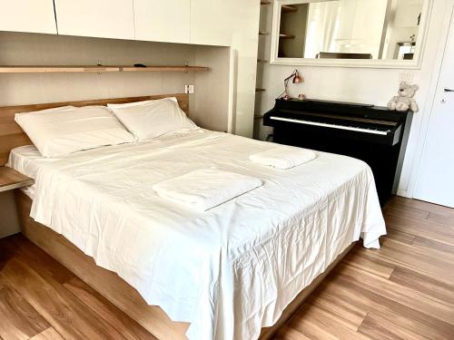 a bedroom with a bed with white sheets and a piano at white home near Linate in Segrate