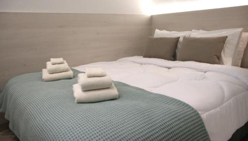 Una gran cama blanca con toallas encima. en CasaTu Αpartments, en Komotiní