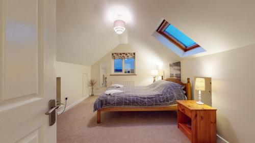 a bedroom with a bed and a skylight at Jaw-Dropping Beach House In Anglesey in Benllech