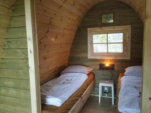 Duas camas num pequeno quarto com uma janela em Luxe glamping "De Steenuil" met sauna em Volkel
