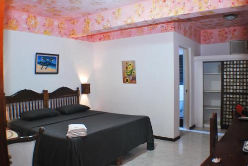 a bedroom with a bed with a black blanket and pink wallpaper at Blue Coral Resort Boracay in Boracay