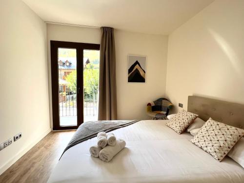 a bedroom with a large white bed with towels on it at Espot Cowork & Apartments - L'Amfitriona in Espot