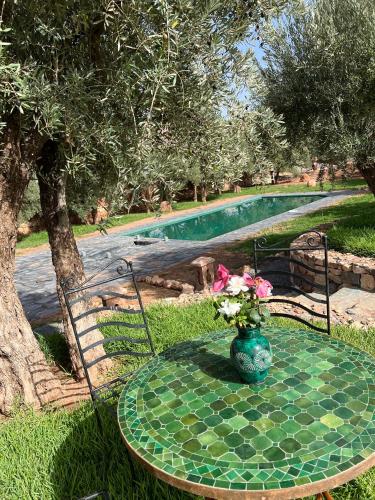 a table with a vase of flowers on it next to a pool at Bin Jbal Resort in Ouirgane