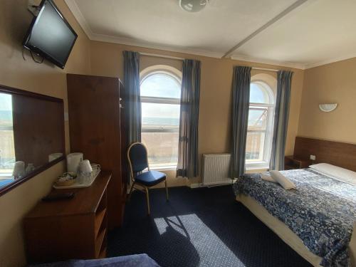 フォークストンにあるOYO Gran Canaria Hotelのベッド、デスク、窓が備わるホテルルームです。