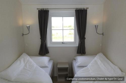 デン・ホールンにあるCamping Loodsmansduinのベッド2台と窓が備わる客室です。