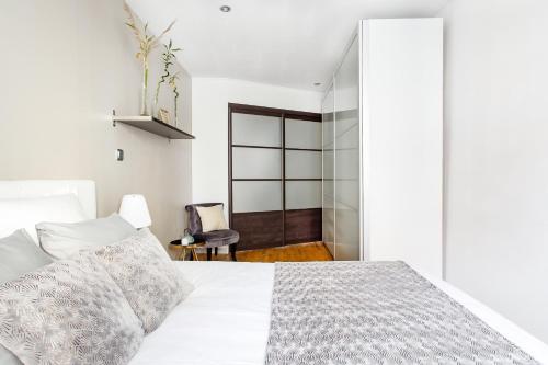 a white bedroom with a bed and a chair at L'Authentik, charme et confort en vieille ville in Annecy