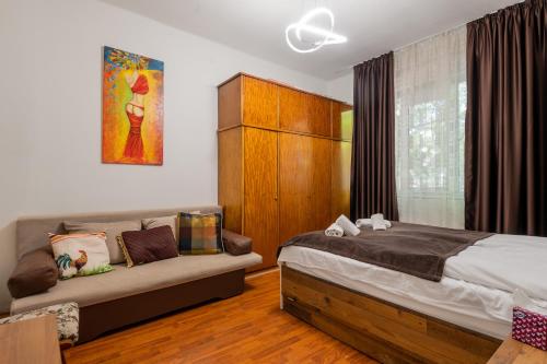 een slaapkamer met een bed en een bank bij National Palace of Culture View - Spacious 1-BD Flat in Sofia