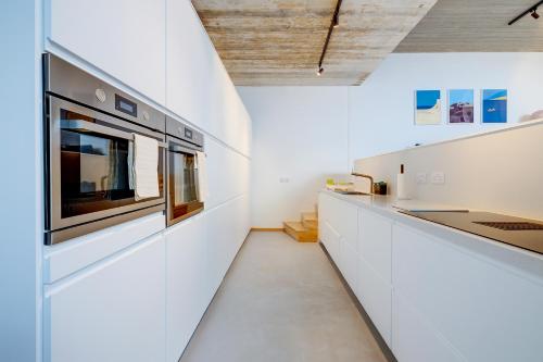 a kitchen with white cabinets and a stove at Traditional Maltese Townhouse wt Terrace and Pool in Senglea