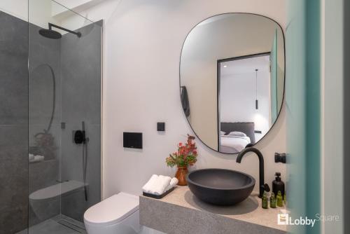 La Mer Apartment by LobbySquare في بيرايوس: حمام مع حوض أسود ومرآة