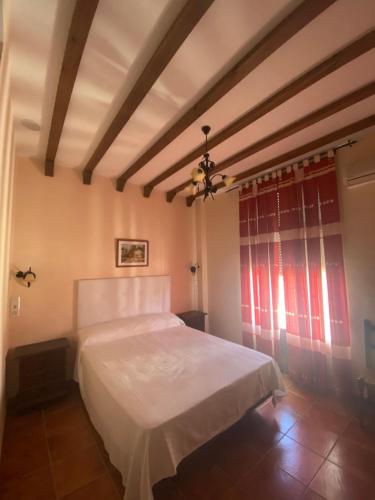 1 dormitorio con cama blanca y ventana en Hotel Meson Fuente del Pino, en Olvera