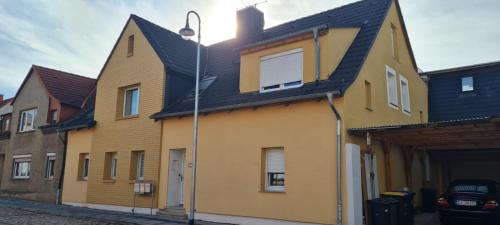 a yellow house with a black roof on a street at Zollzeche Stadtwohnungen in Staßfurt