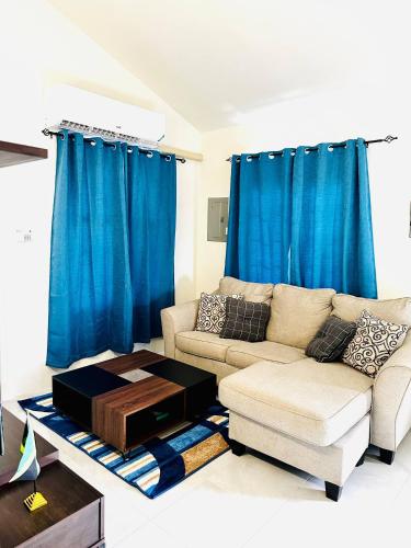 a living room with a couch and blue curtains at Escape to Paradise Brand New Bungalow with Ocean View in Discovery Bay 1 in Discovery Bay