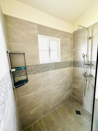 a bathroom with a shower with a mirror and a window at Escape to Paradise Brand New Bungalow with Ocean View in Discovery Bay 1 in Discovery Bay