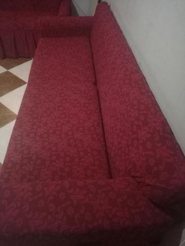 a red couch sitting in the corner of a room at Zeina in Minshāt Kamāl