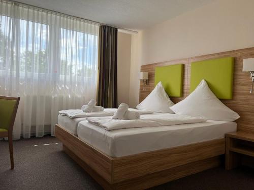 Hotel Ziegenkrug - Pritzwalk في بريتسفالك: غرفة نوم بسرير كبير عليها حشرتين محشوتين