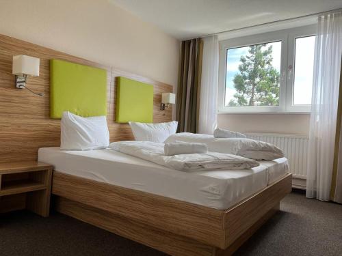 a bedroom with a large bed with a large window at Hotel Ziegenkrug - Pritzwalk in Pritzwalk