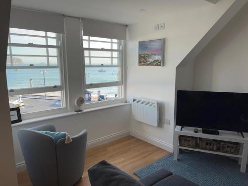 a living room with a flat screen tv and views of the beach at Apartment - Centre of Swanage Stunning Sea views in Swanage