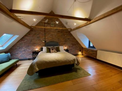 a loft bedroom with a bed and a brick wall at Stunning 3BD Character House near Coleshill in Birmingham