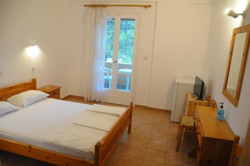 Dormitorio con cama, escritorio y TV en Chalikias Rooms, en Asprogerakata