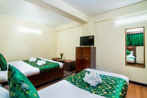 a hotel room with two beds and a television at Muscatel BhumSang - 200 Mts from Mall Road in Darjeeling