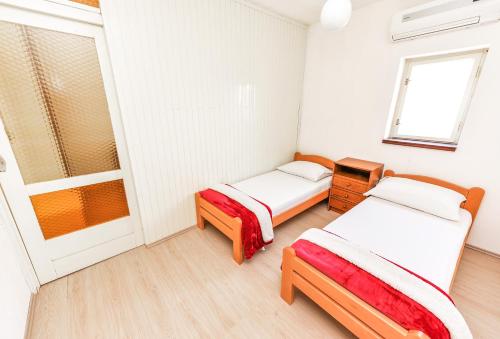 Cette chambre comprend 2 lits et une fenêtre. dans l'établissement Apartments Brezovka, à Novalja