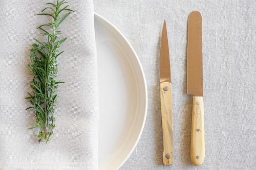a white plate with a knife and a sprig of herbs at Casa Mon in Monforte dʼAlba