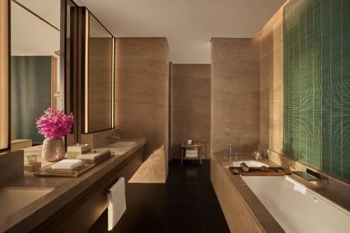ein Badezimmer mit einer Badewanne und einem Waschbecken mit einer Blumenvase in der Unterkunft Regent Phu Quoc in Phu Quoc
