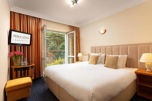 um quarto de hotel com uma cama grande e uma janela em Perła Leśna Nadarzyn em Nadarzyn