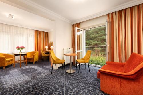 pokój hotelowy z pomarańczowymi krzesłami i stołem w obiekcie Perła Leśna Nadarzyn w mieście Nadarzyn