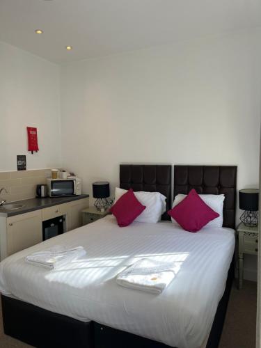 a bedroom with a large bed with pink pillows at Kings Hotel in Newmarket