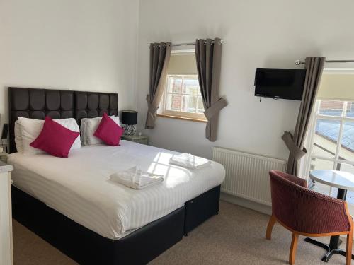 a bedroom with a bed with pink pillows and a tv at Kings Hotel in Newmarket