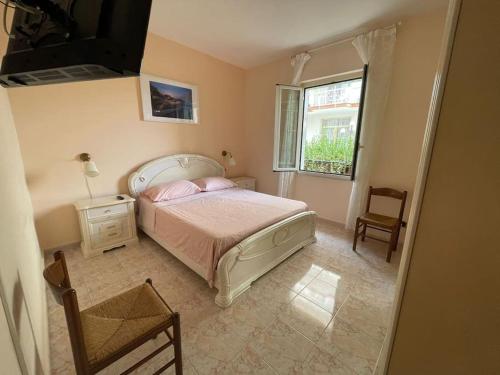 ein Schlafzimmer mit einem Bett, einem Fenster und einem Stuhl in der Unterkunft Appartamento 10 m dal mare Casa da zia Lena Maiori in Maiori