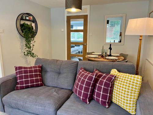 een woonkamer met een grijze bank en kleurrijke kussens bij Chic 2BR Haven - Contemporary Flat in Hoddesdon in Hoddesdon