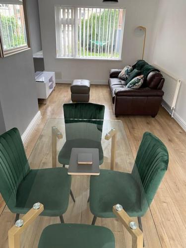 uma sala de estar com cadeiras verdes e um sofá em Pontymister Retreat em Risca