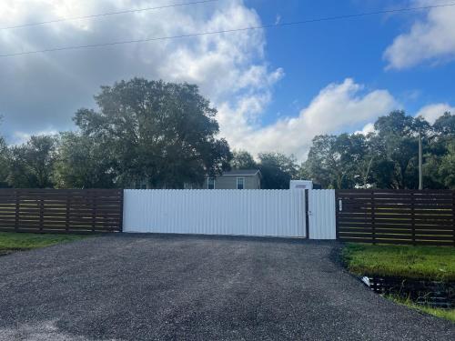 a white fence next to a gravel driveway at The Perfect Get Away !!!! in Clewiston