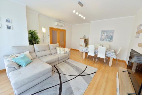 a living room with a couch and a dining room at FLORIPES LUXURY APARTMENT with Pool on Rooftop in Olhão