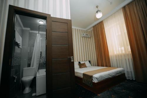 ein kleines Schlafzimmer mit einem Bett und einem Badezimmer in der Unterkunft FAYZ in Urganch