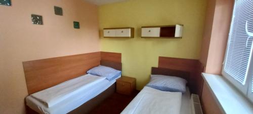 Cette petite chambre comprend 2 lits et une fenêtre. dans l'établissement Expres Atack Penzion, à Brno