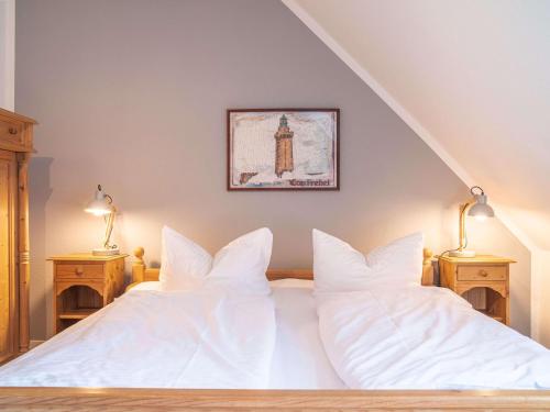 a bedroom with a bed with white sheets and two lamps at Ferienhaussiedlung Strandperlen Sanddornhof 5b (Typ V) in Wustrow