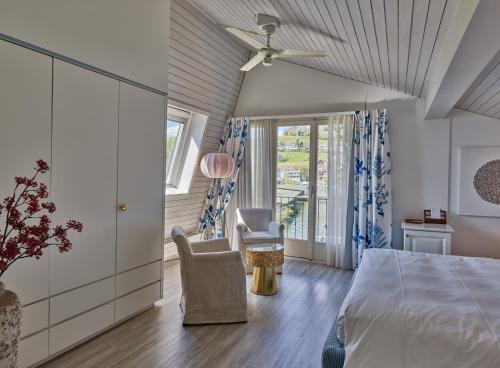 a bedroom with a bed and a chair and a window at Strandhotel Schmerikon in Schmerikon