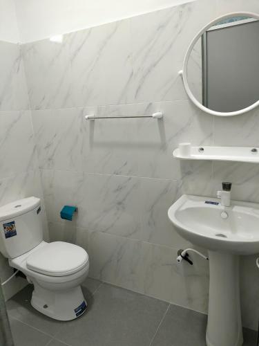 a white bathroom with a toilet and a sink at Victory's Gardens in Mannar
