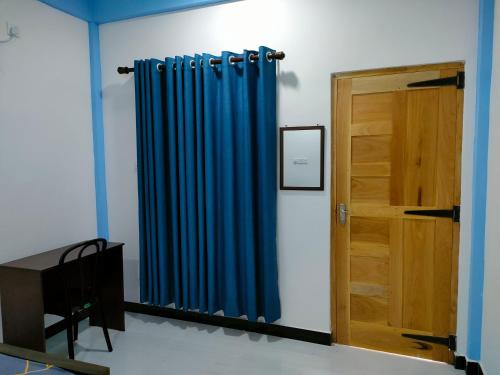 a room with a blue curtain and a wooden door at Victory's Gardens in Mannar