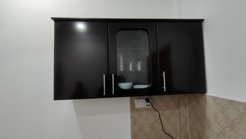 a black cabinet hanging on a wall at Victory's Gardens in Mannar