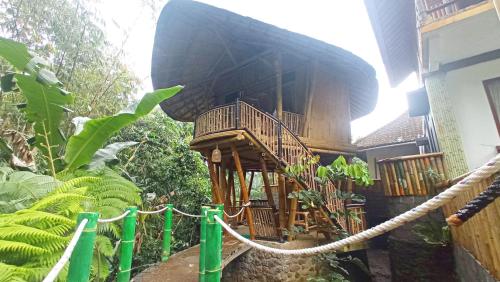 a wooden building with a balcony in a garden at Pondok Salacca#bamboohouse# in Candidasa