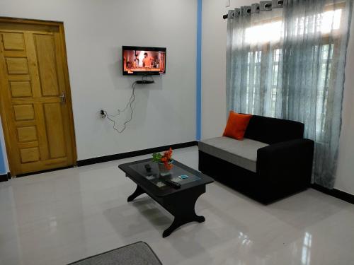 a living room with a couch and a table and a tv at Victory's Gardens in Mannar