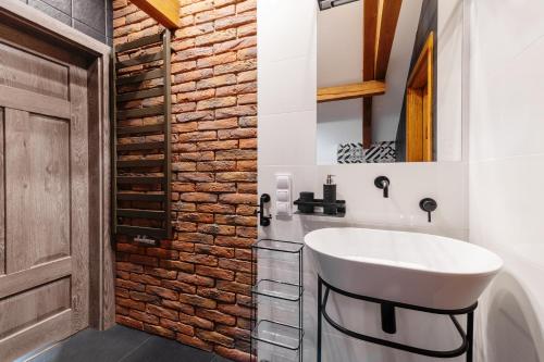 ein Badezimmer mit einem weißen Waschbecken und einer Ziegelwand in der Unterkunft Gostynin Garden Apartment III in Gostynin