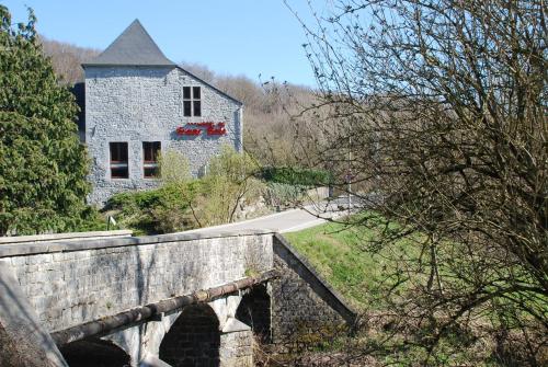 una casa de piedra con flores rojas en un puente en Hotel De Franc Bois, en Chimay