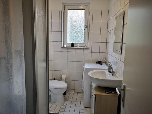 Un baño con lavabo, inodoro y ventana. en POLAT Apartments 3, en Essen