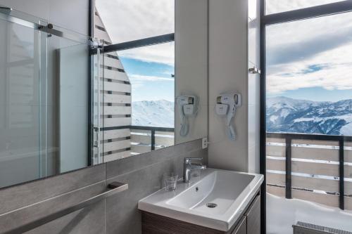 een badkamer met een wastafel, een spiegel en bergen bij Gogi Ski Resort in Goedaoeri